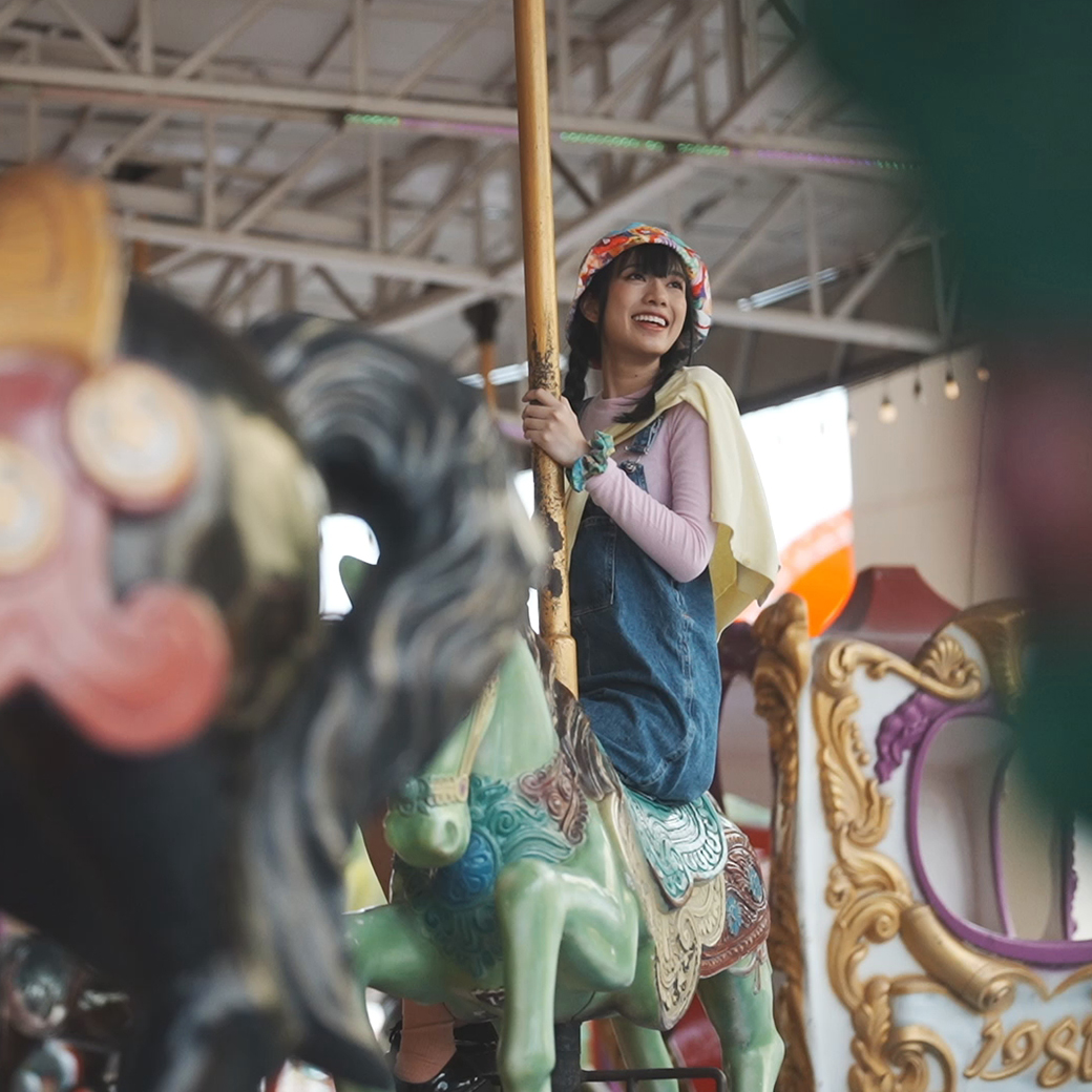 Girl riding on a green horse on a merry-go-round