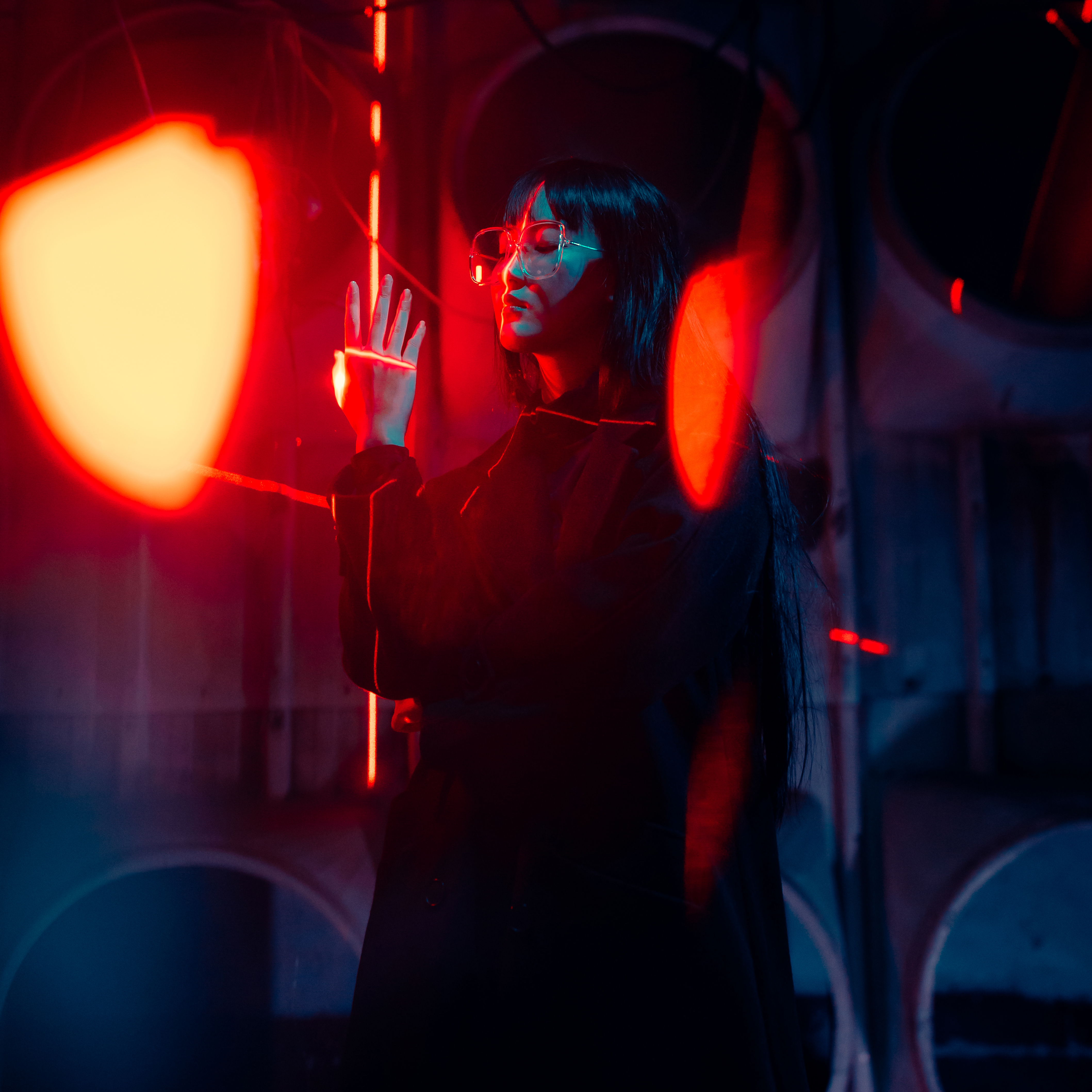 Frontal side view of girl looking at her raised hand in front of red laser lights